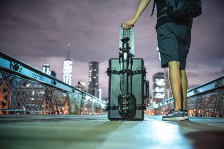 Natmotiv med person der g&aring;r med en Manfrotto trolly kuffert p&aring; en oplyst bro