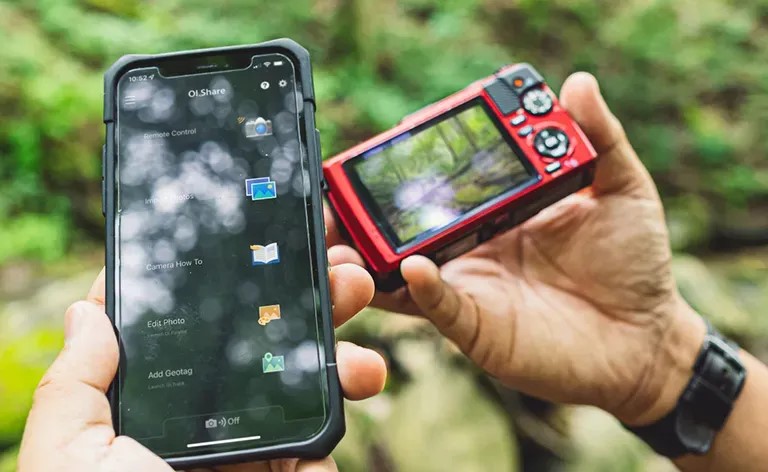 Billede af mand der holder sin smartphone ved siden af sit TG-7 som illustration p&aring; at de kan forbindes via direkte WIFI